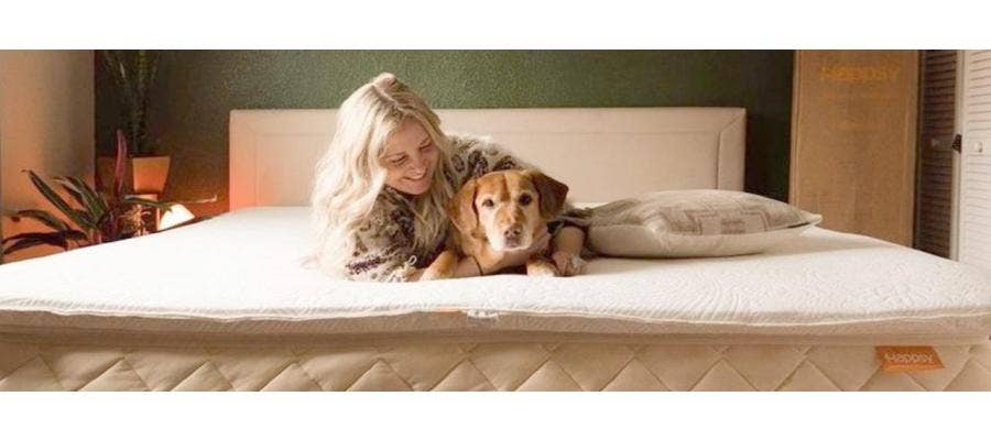 Smiling woman cuddling a brown dog on a Happsy mattress