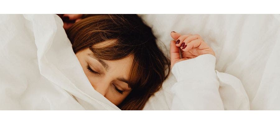Woman soundly sleeping under a white duvet