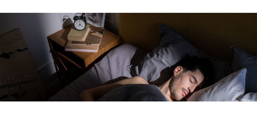 Man sleeping in a darkened room with a bar of sunlight streaming in