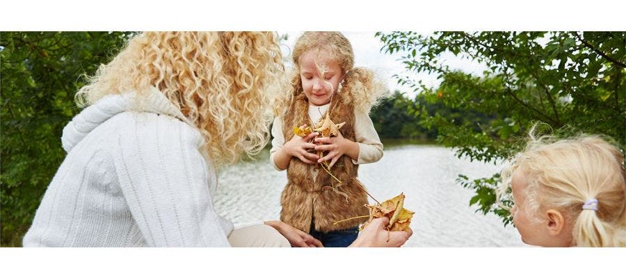 mother and two daughters holding autumn leaves