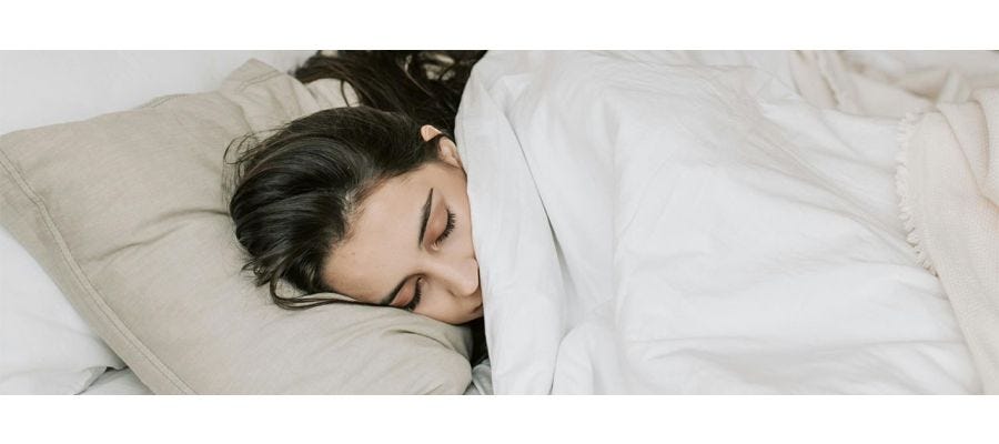 woman laying on pillow with white duvet