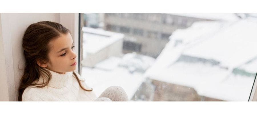 Woman hugging her knees to her chest , dealing with the winter blues