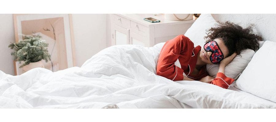 person laying in bed with sleep mask on