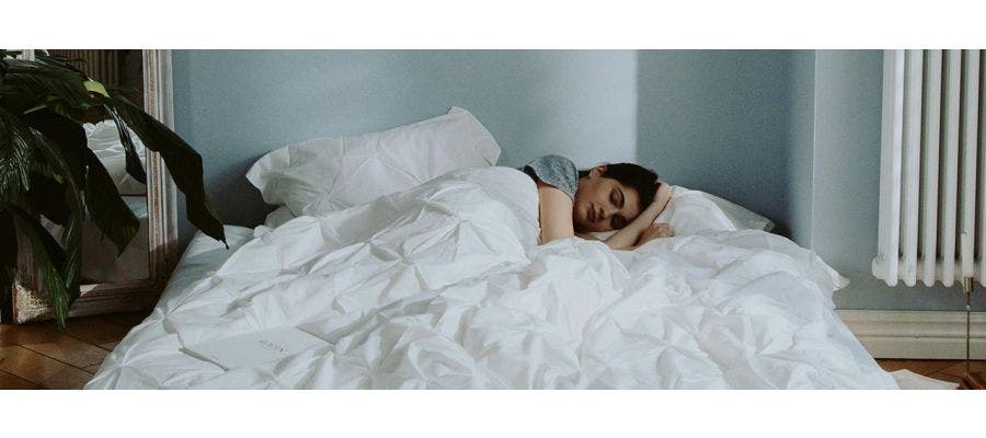 person sleeping in a bed with white bedding
