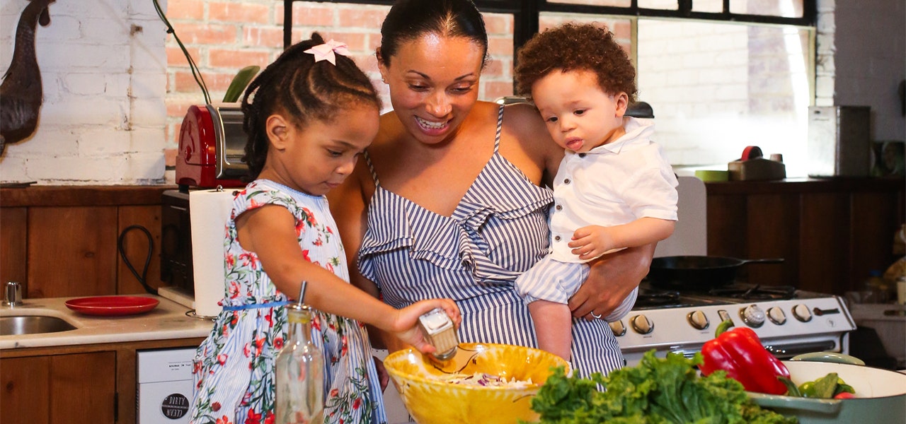 Smiling mom and two small kids cooking together