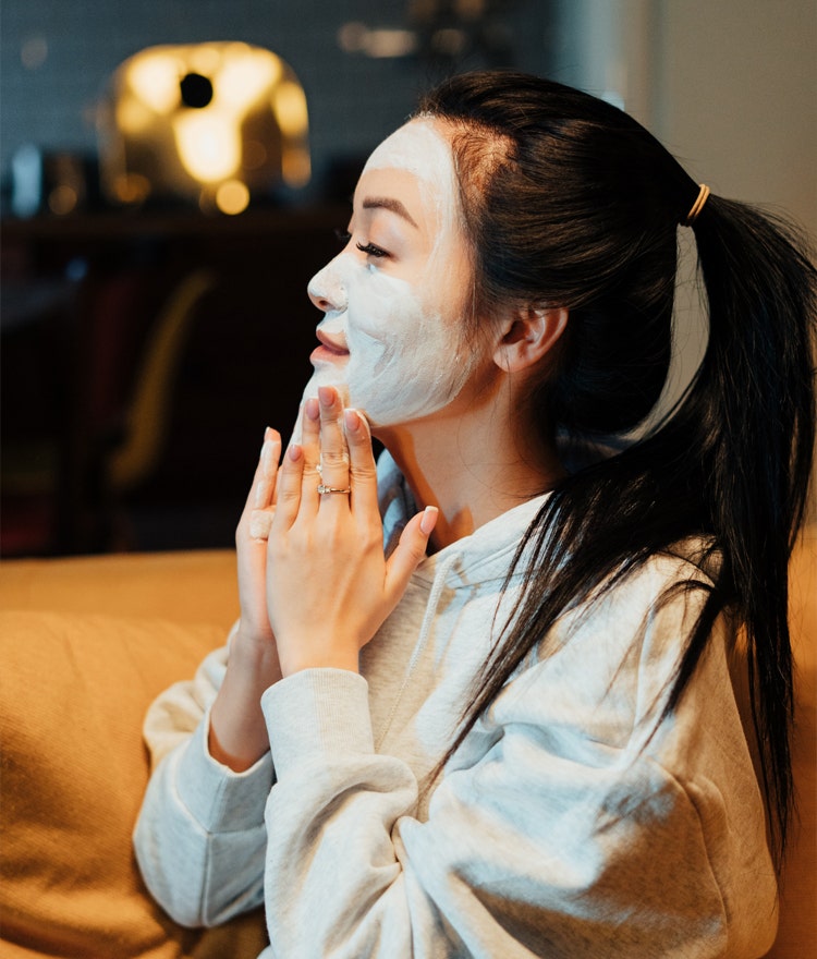 Young woman in comfy clothes applying a DIY face mask