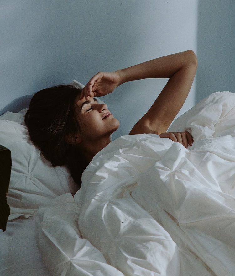 Woman waking up tired in a naturally lit bedroom