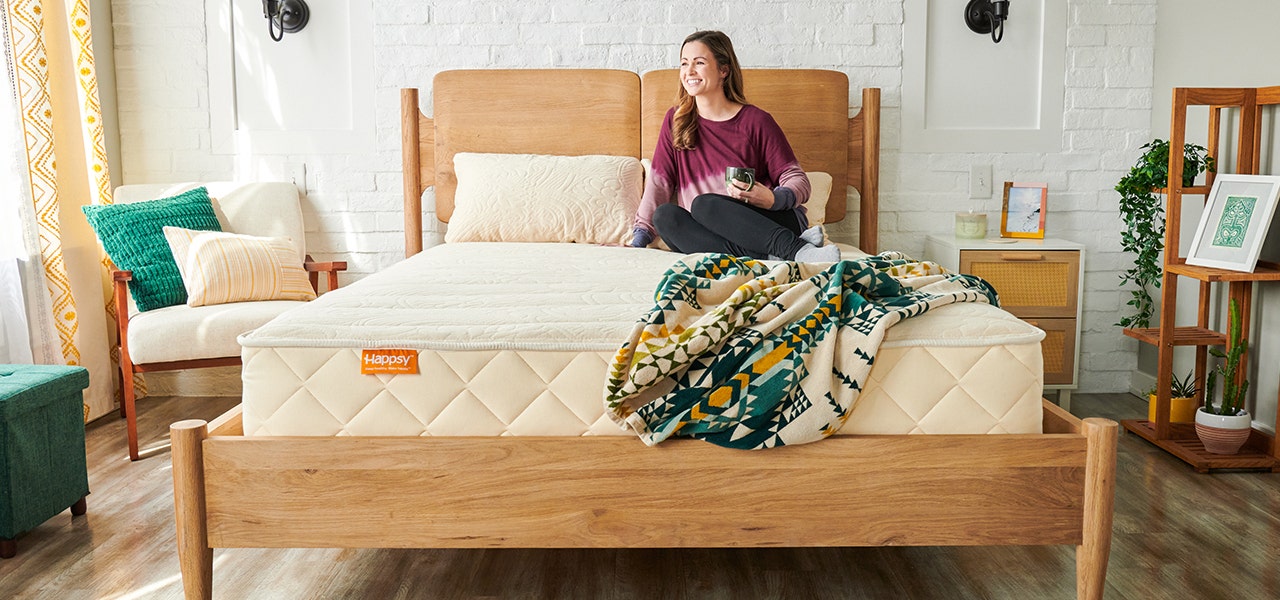 Woman relaxing with a cup of coffee on her Happsy organic mattress