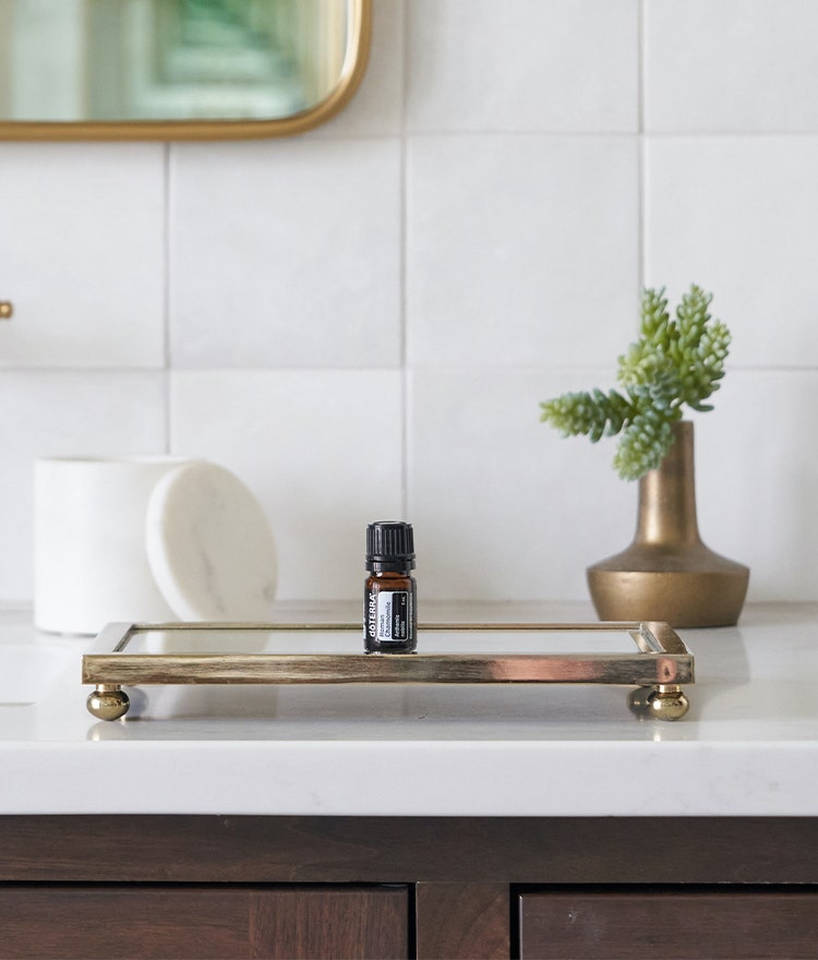 Bottle of essenital oil on a glass tray on bathroom counter