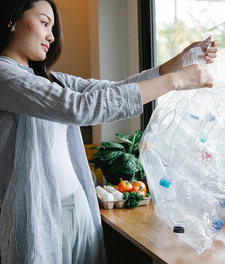 Woman tying up a bag of plastic recycling