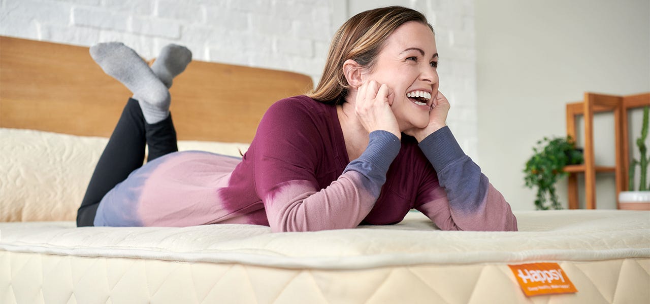 woman laying on happsy organic mattress and smiling