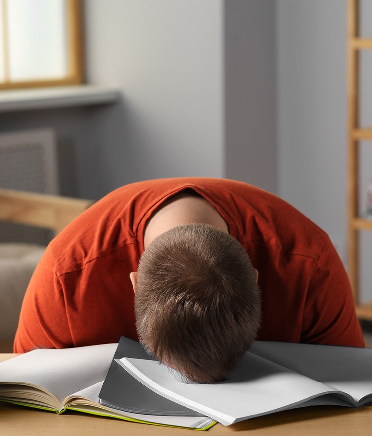 Young man asleep at the table with his schoolwork