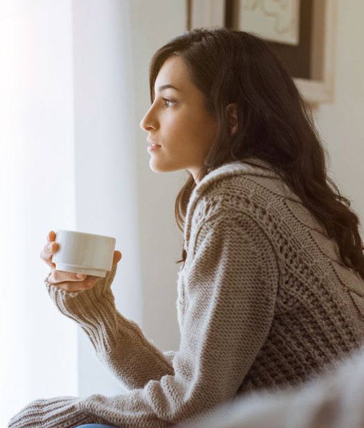 Woman drinking coffee and looking out the window
