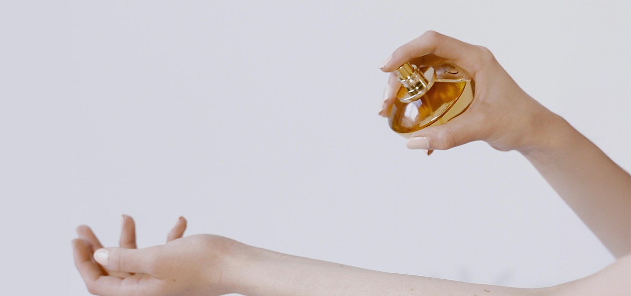 hand spraying bottle of fragrance on skin
