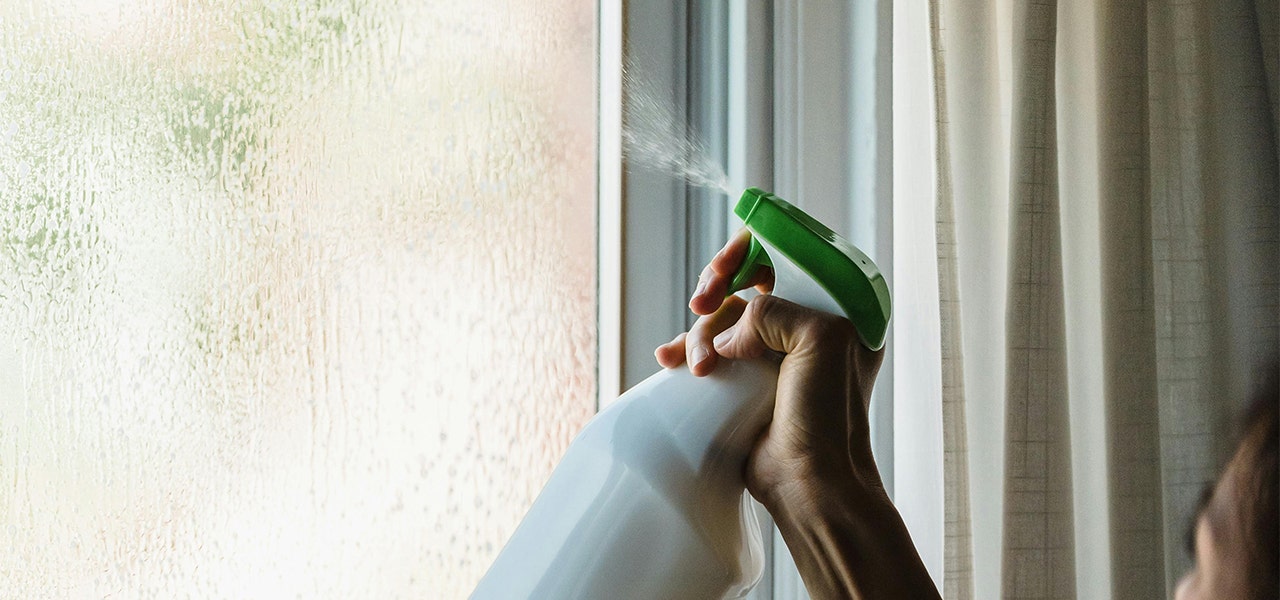 hand spraying cleaning product on glass