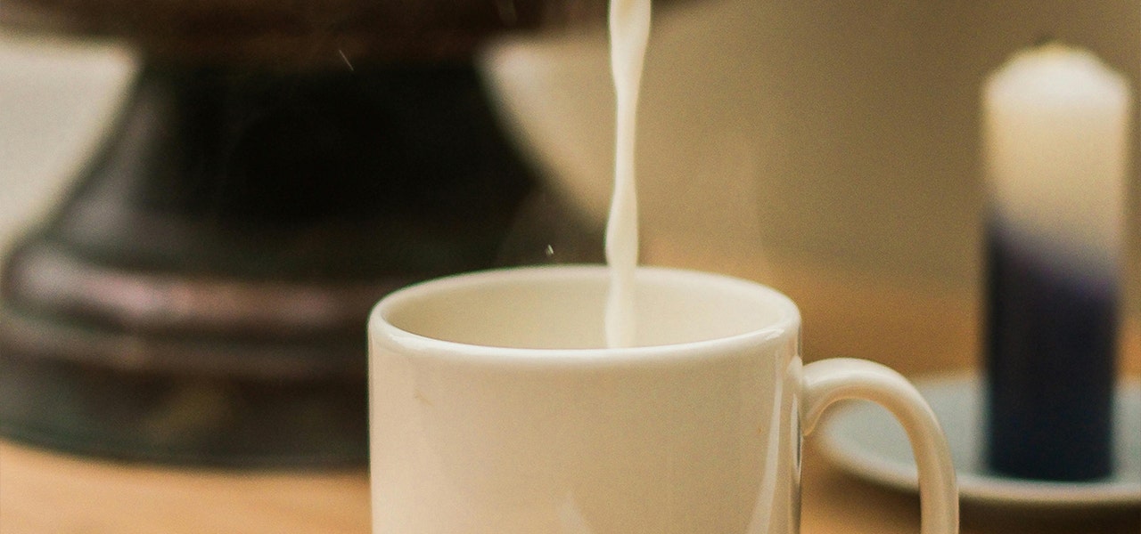 milk being poured into a white mug