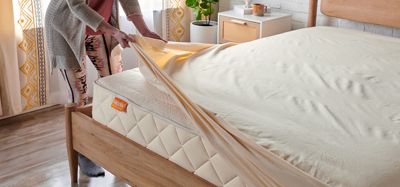 putting a happsy organic mattress protector pad on a happsy organic mattress