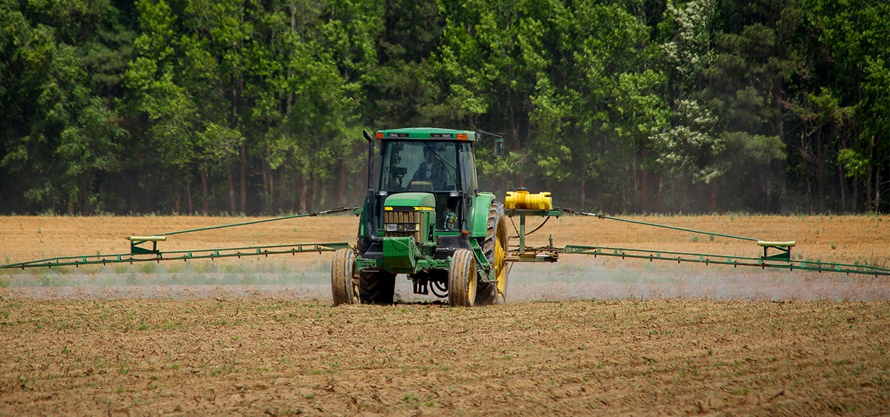 tractor spraying cotton plants with pesticides