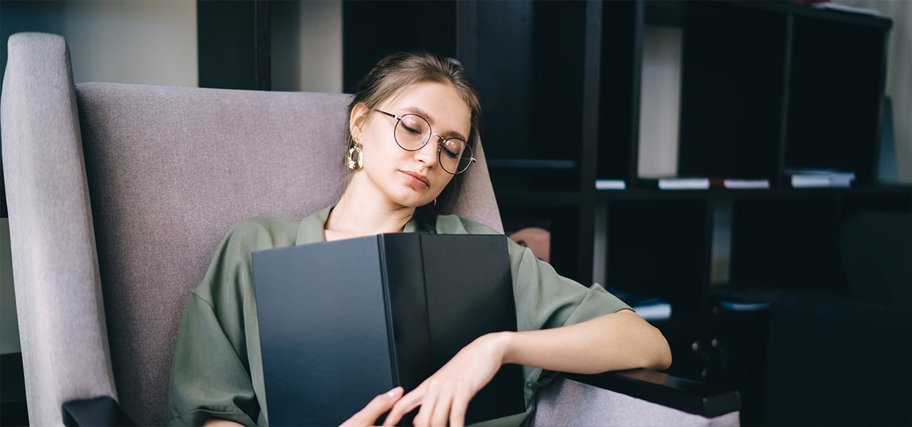 woman sleeping in an armchair with a book