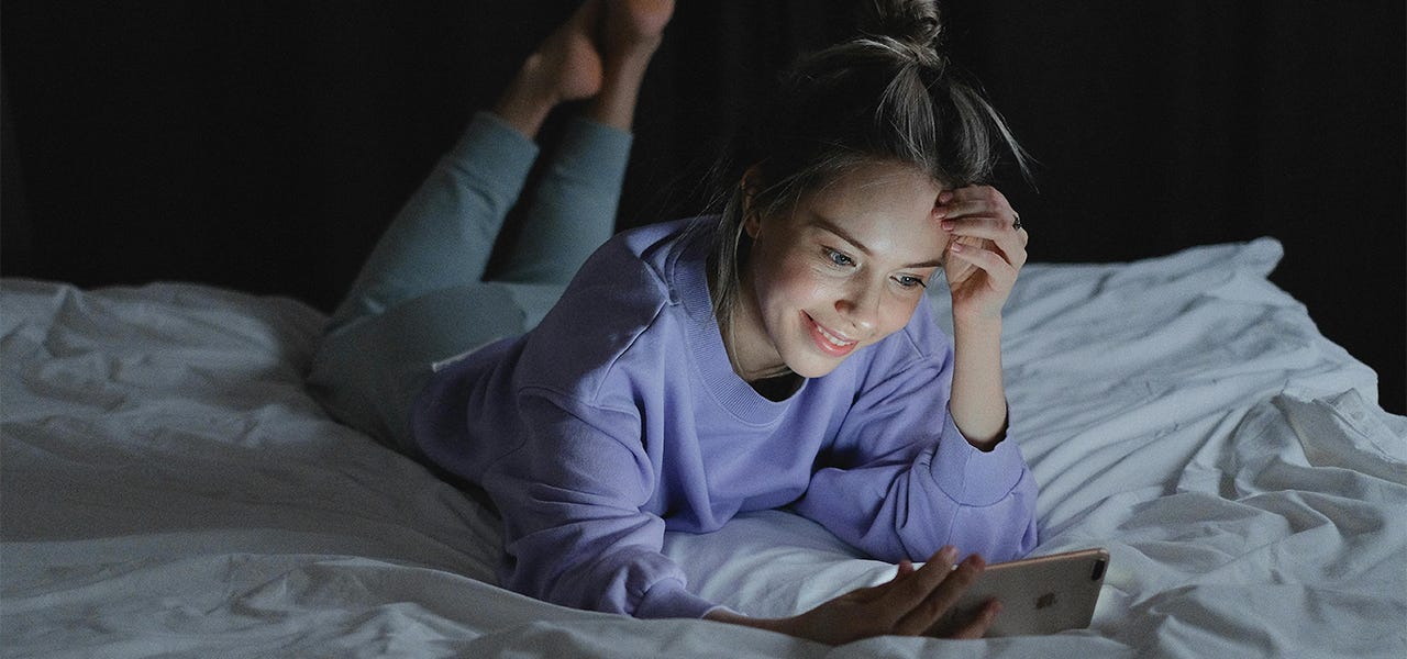 woman looking at her phone in bed at night