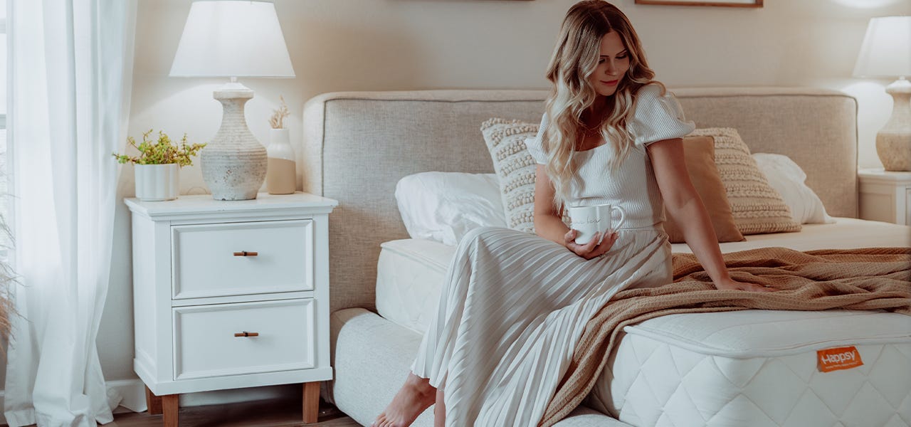 woman sitting on a happsy organic mattress in a modern bedroom