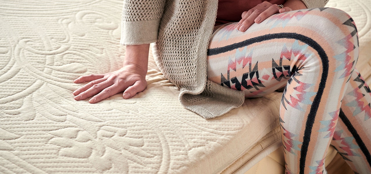 sitting on a bed with happsy organic mattress topper